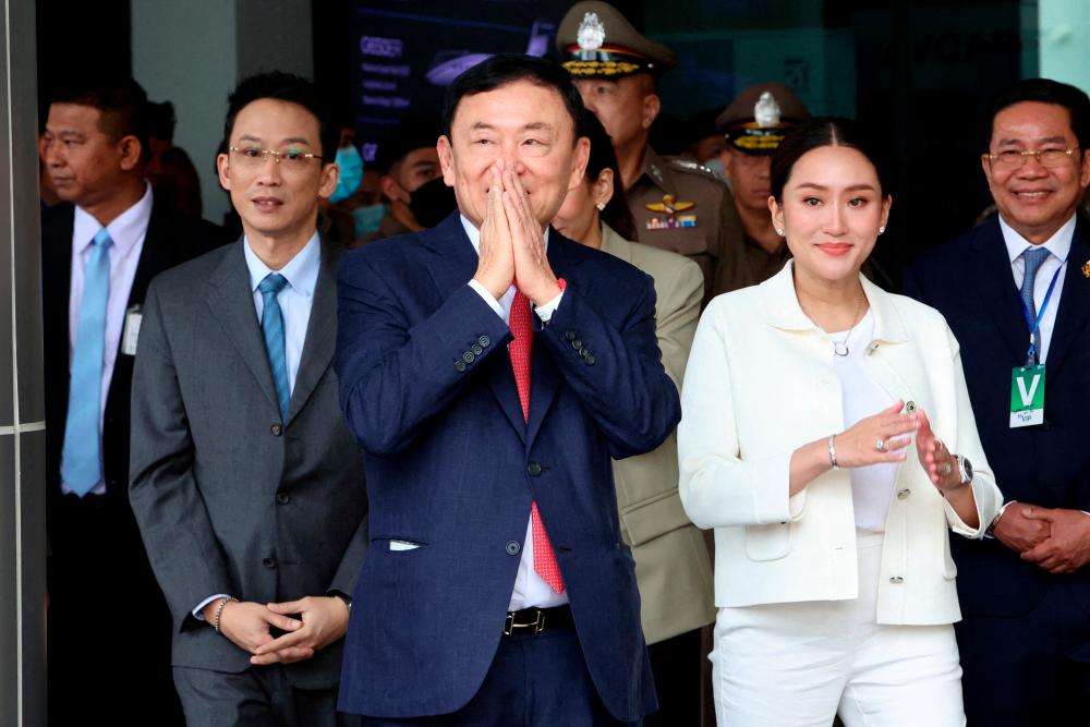 Former Thai Prime Minister Thaksin Shinawatra, who is expected to be arrested upon his return as he ends almost two decades of self-imposed exile, gestures while flanked by his son Panthongtae Shinawatra and daughter Paetongtarn Shinawatra at Don Mueang airport in Bangkok, Thailand August 22, 2023/REUTERSPix