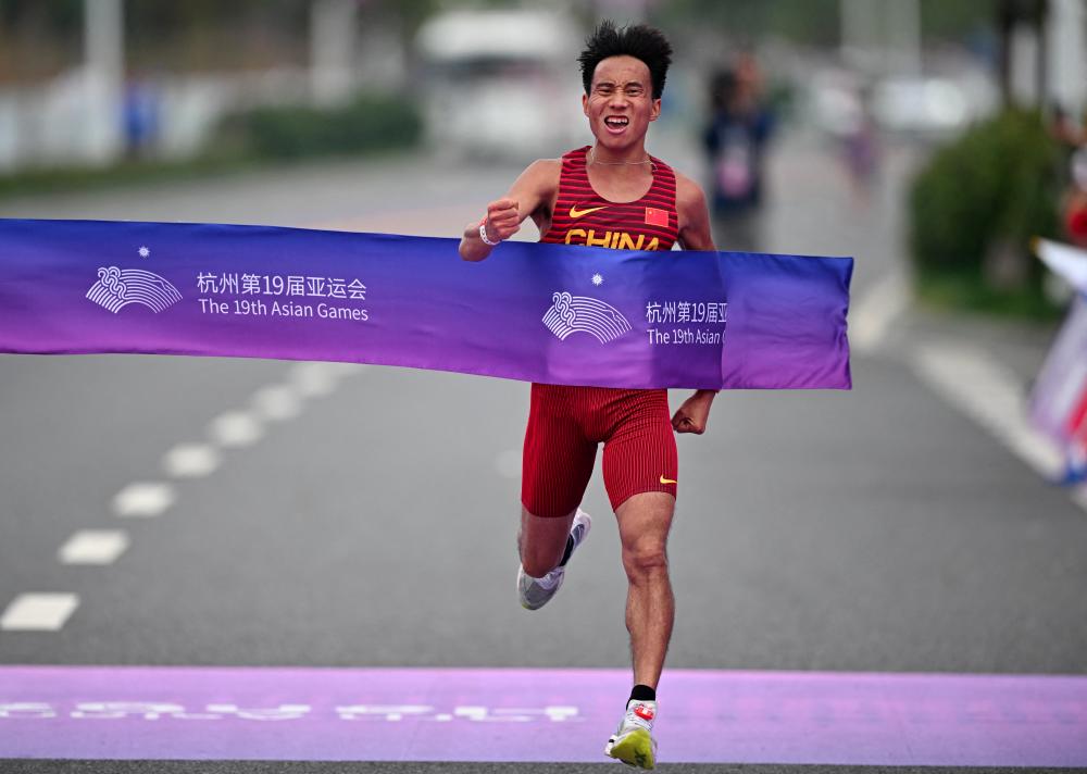 Asian Games - Hangzhou 2022 - Marathon - Qiantang River Green Belt, Hangzhou, China - October 5, 2023 China's He Jie crosses the line to win the gold medal in the Men's Marathon Final - REUTERSPIX