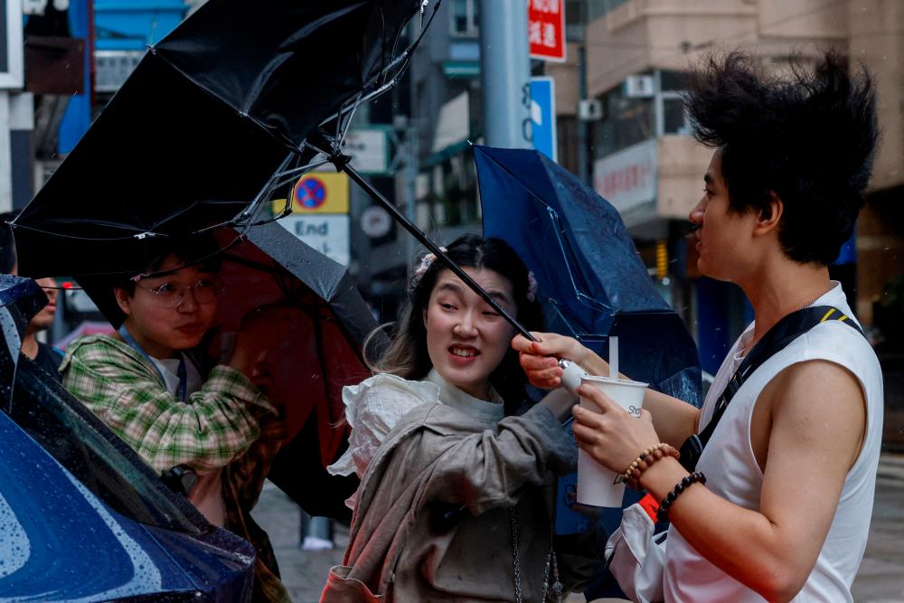 People struggle with umbrellas while walking against strong wind, as Typhoon Koinu approaches, in Hong Kong, China October 8, 2023. REUTERSPIX