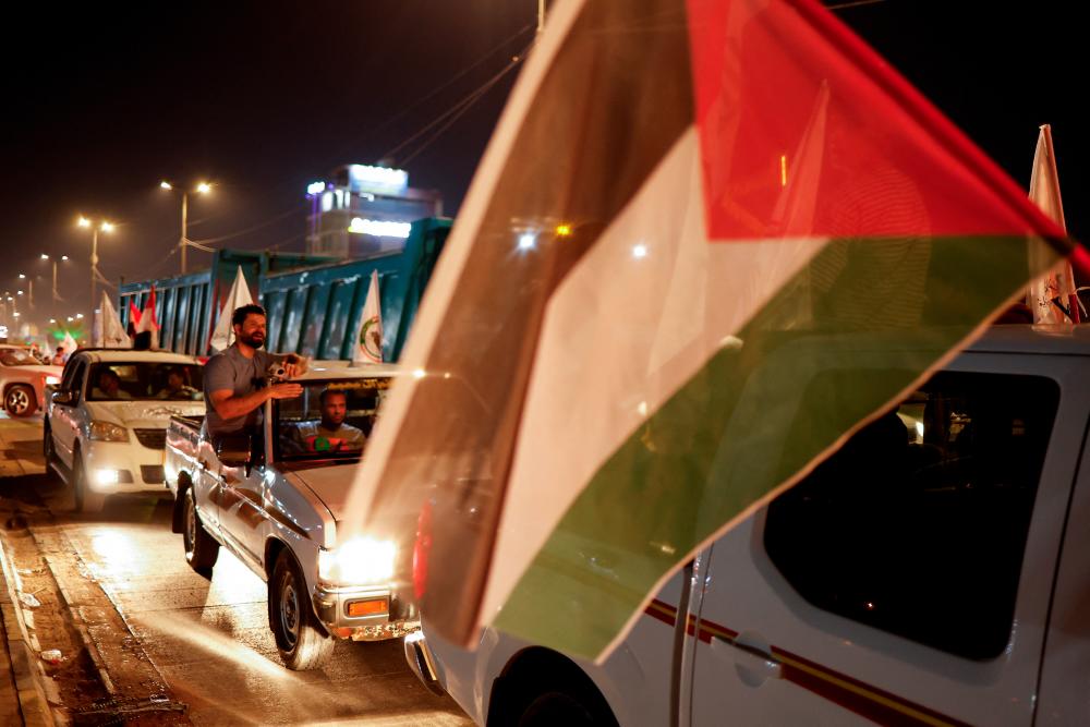 People wave flags from their vehicles during a protest in solidarity with Palestinians in Gaza, in Najaf, Iraq, October 8, 2023. REUTERSPIX