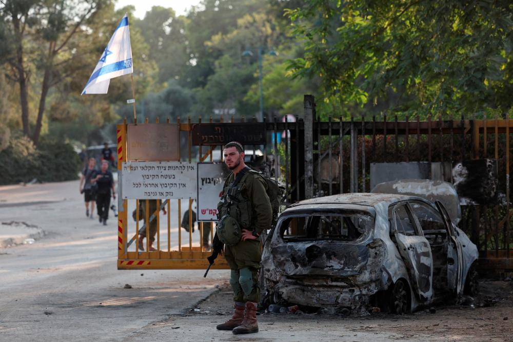 An Israeli soldier stands at the entrance to kibbutz, in the aftermath of a mass infiltration by Hamas gunmen from the Gaza Strip, in Kibbutz Beeri in southern Israel, October 14, 2023. - REUTERSPIX