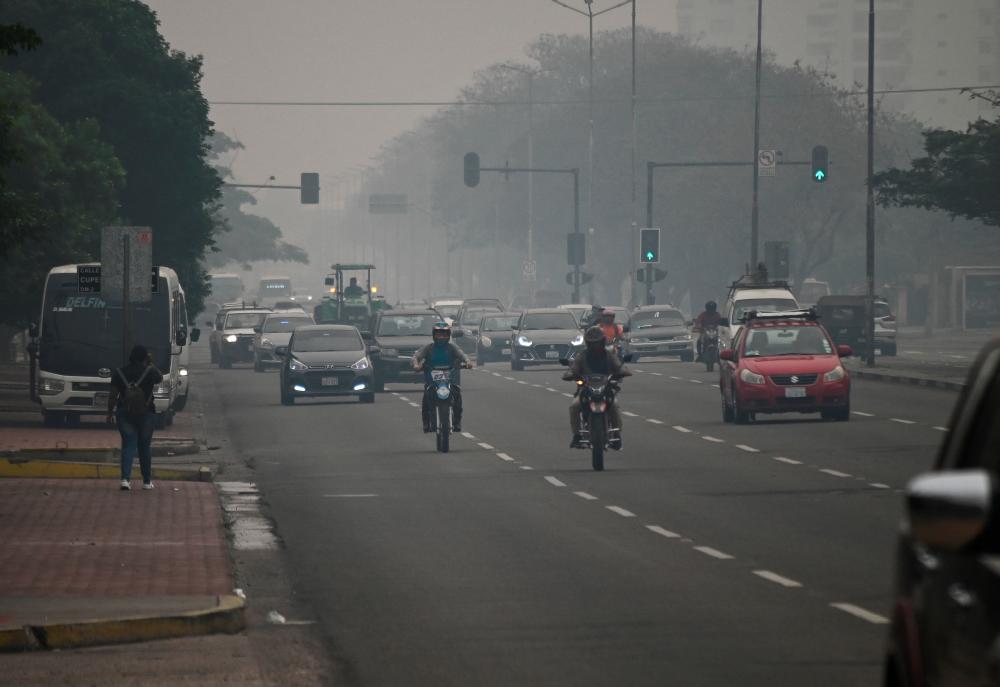 People walk and drive through the city shrouded in smoke caused by wildfires in the area, which prompted the local government to issue a red sanitary alert due to the heavy pollution, in Santa Cruz, Bolivia October 24, 2023. REUTERSPIX