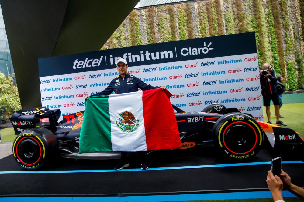 Red Bull's Sergio Perez poses for pictures holding a Mexican flag in front of his car during a press conference at the Plaza Carso in Mexico City, Mexico October 25, 2023. REUTERSPIX