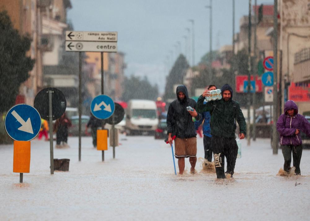 People walk in a flooded street in the aftermath of Storm Ciaran, in Oste, in Tuscany region, Italy, November 3, 2023. - REUTERSPIX