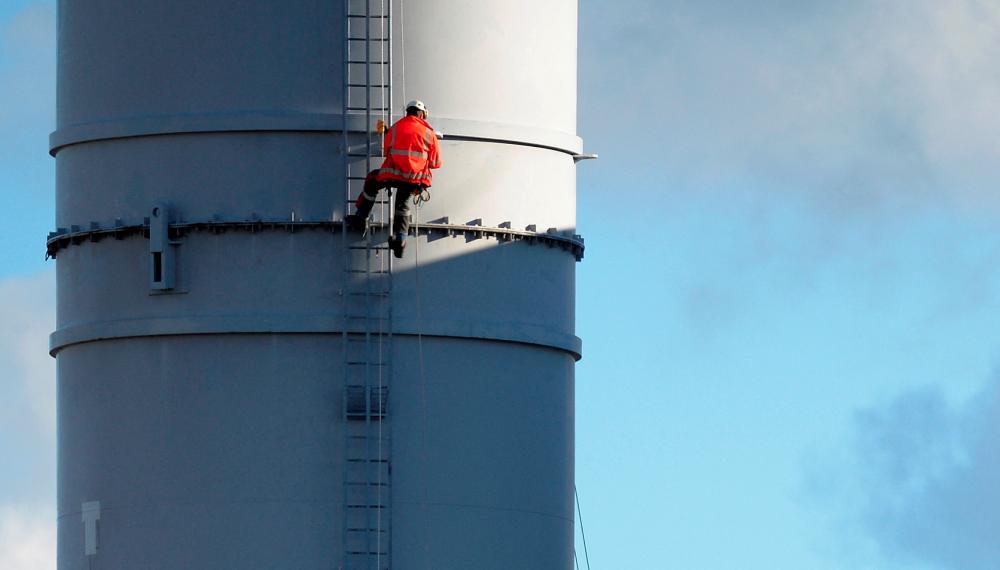 FILE PHOTO: A worker scales one of the towers at the Grangemouth refinery, Scotland, October 24 2013. - REUTERSPIX