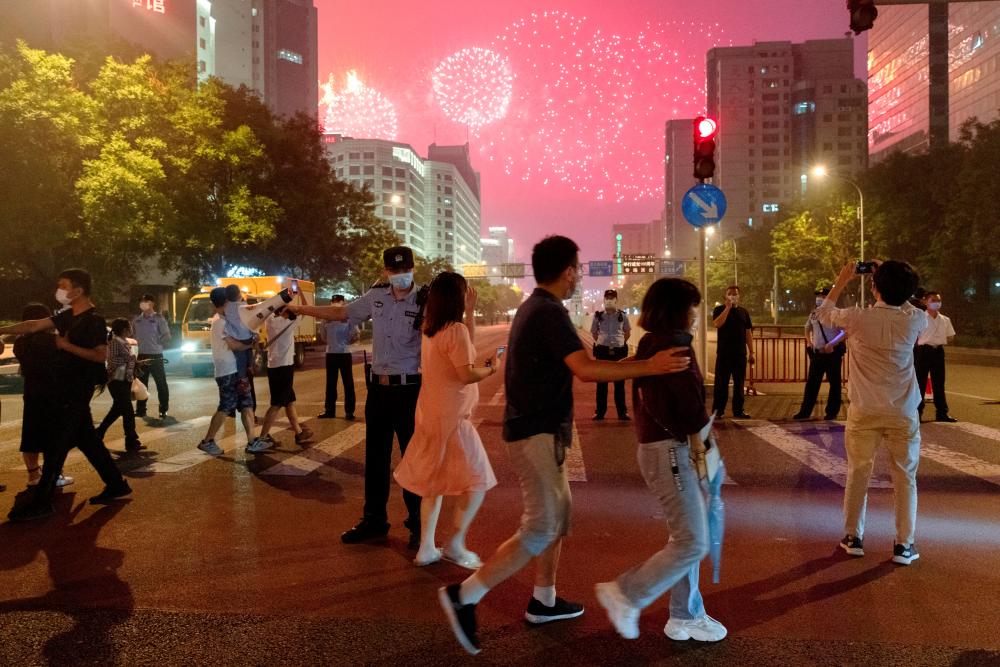 FILE PHOTO: People watch a rehearsal of a fireworks display near the National Stadium ahead of the 100th founding anniversary of the Communist Party of China in Beijing, China June 25, 2021. - REUTERSPIX