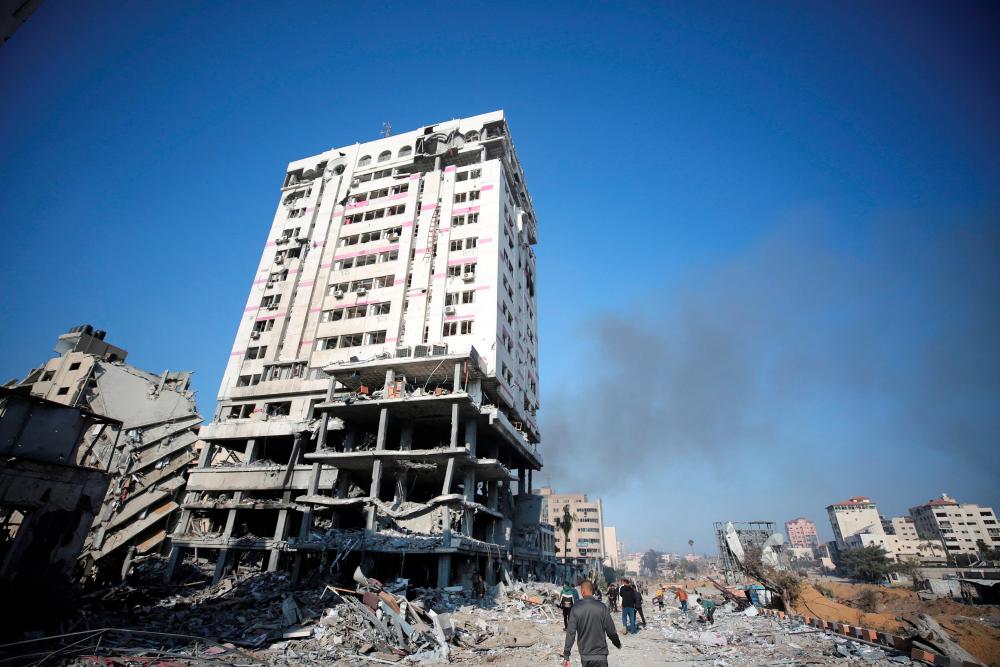 Palestinians walk near the damaged building of Bank of Palestine following an Israeli ground operation, amid the ongoing conflict between Israel and Hamas, in Gaza City, February 10, 2024. - REUTERSPIX