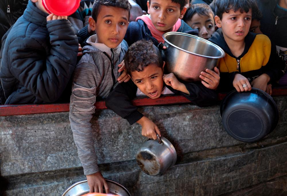 Filepix: Palestinian children wait to receive food cooked by a charity kitchen amid shortages of food supplies, as the ongoing conflict between Israel and the Palestinian Islamist group Hamas continues, in Rafah, in the southern Gaza Strip, February 5, 2024/REUTERSPix