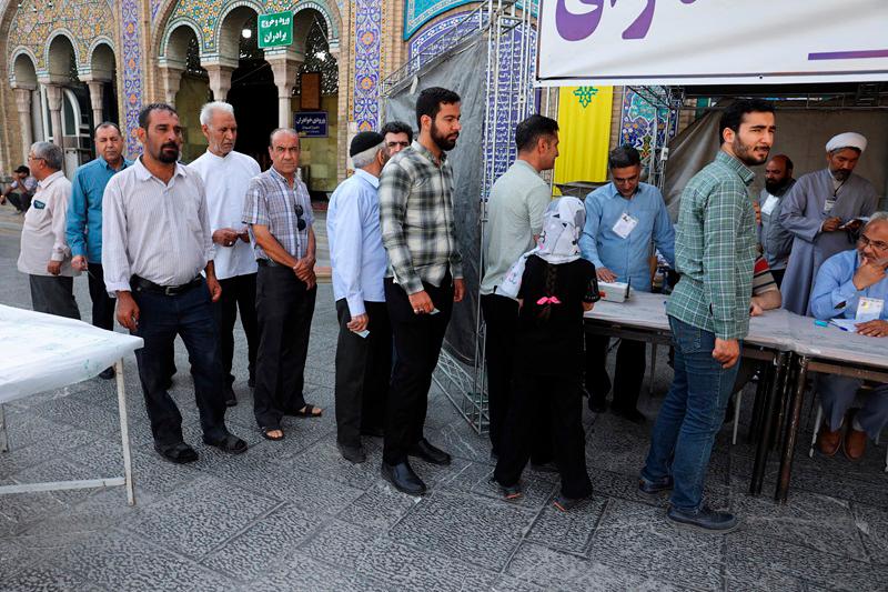 Iranian people stand in a queue as they wait to vote at a polling station in a snap presidential election to choose a successor to Ebrahim Raisi following his death in a helicopter crash, in Tehran, Iran June 28, 2024. Majid Asgaripour/WANA (West Asia News Agency) via REUTERS