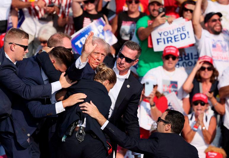 Republican presidential candidate and former U.S. President Donald Trump gestures with a bloodied face while he is assisted by U.S. Secret Service personnel after he was shot in the right ear during a campaign rally - REUTERSpix