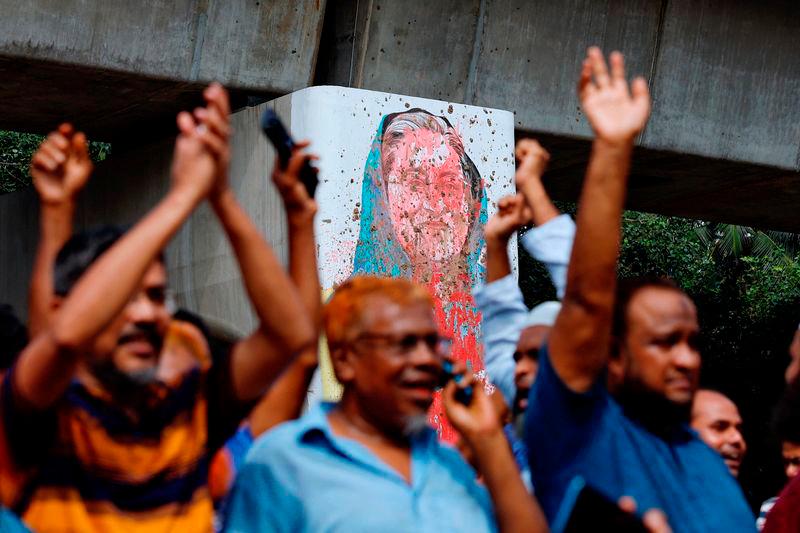 A mural of Prime Minister Sheik Hasina is seen vandalised by protesters as people celebrate her resignation in Dhaka - REUTERSpix