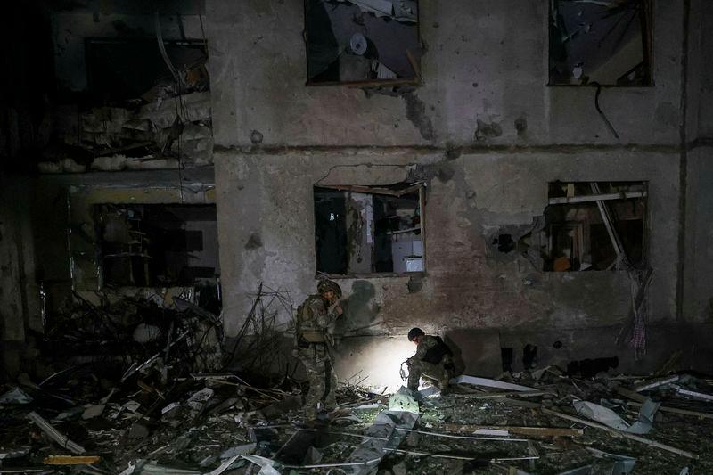 Police officers search parts of a bomb at a site of an apartment building hit by a Russian air strike, amid Russia’s attack on Ukraine, in Kharkiv - REUTERSpix