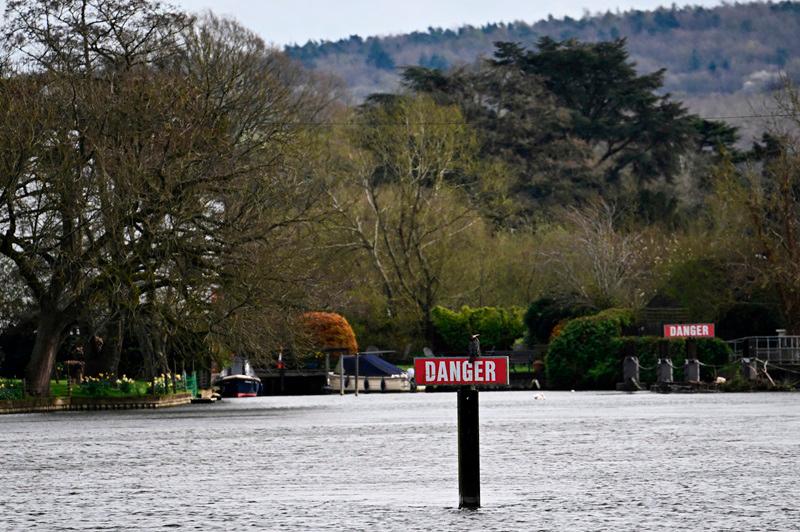 FILE PHOTO: A bird sits atop a Danger sign on the River Thames, on the day data revealed sewage spills into England's rivers and seas by water companies more than doubled last year, in Hambledon, Britain, March 27, 2024. - REUTERS/Dylan Martinez/File Photo