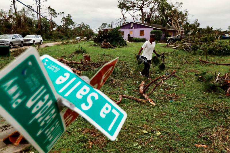 A man picks up debris left by a tornado in a zone affected by Hurricane Milton, in Lakewood Park, Florida. REUTERSPIX