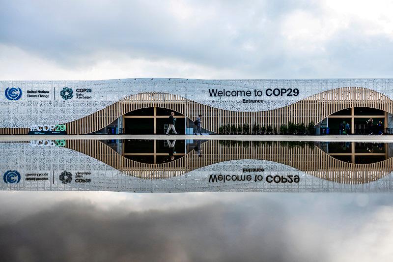 People walk near the entrance to the venue of the United Nations climate change conference, known as COP29, ahead of the summit beginning in Baku, Azerbaijan November 10, 2024. - REUTERS/Maxim Shemetov