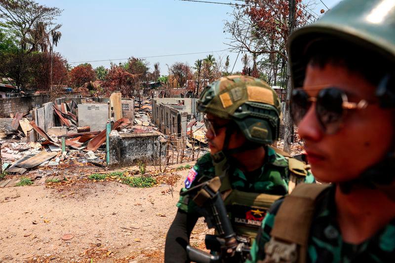 Soldiers from the Karen National Liberation Army (KNLA) patrol on a vehicle, next to an area destroyed by Myanmar's airstrike in Myawaddy, the Thailand-Myanmar border town under the control of a coalition of rebel forces led by the Karen National Union, in Myanmar, April 15, 2024. - REUTERSPIX