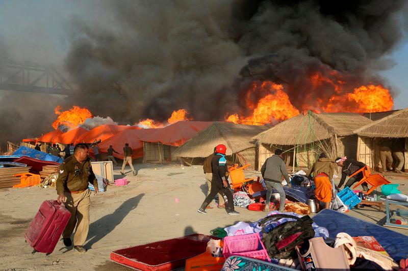 Police officers and volunteers salvage belongings of the devotees after a fire erupts in makeshift tents during the ongoing “Maha Kumbh Mela”, or the Great Pitcher Festival, in Prayagraj, India, January 19, 2025. - REUTERS/Stringer