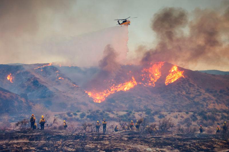 A helicopter drops water as the Hughes Fire burns in Castaic Lake, California - REUTERSpix