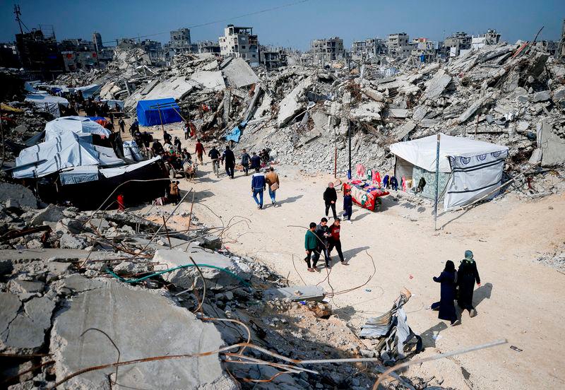 Palestinians walk on a street among the rubble of buildings destroyed during the Israeli offensive, amid a ceasefire between Israel and Hamas, at Jabalia refugee camp - REUTERSpix