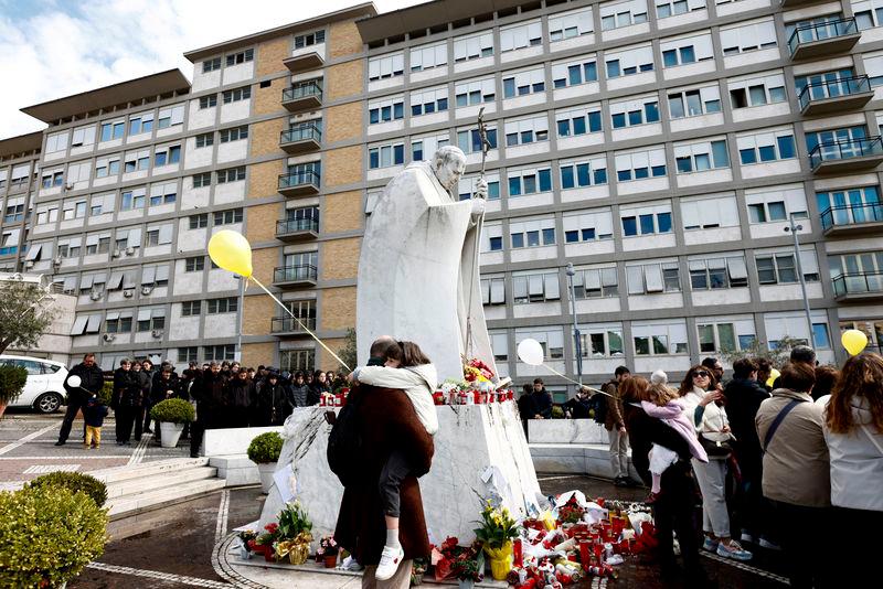 People gather near the statue of late Pope John Paul II outside Gemelli hospital where Pope Francis is admitted to continue treatment for ongoing pneumonia, in Rome, Italy, March 16, 2025. REUTERSpix