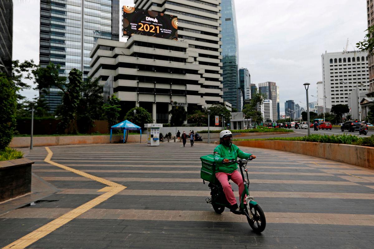 A driver working for the ridesharing company Grab wears a protective mask at a sidewalk near the business district, on the first business day of the New Year, in Jakarta, Indonesia, January 4, 2021. REUTERSpix