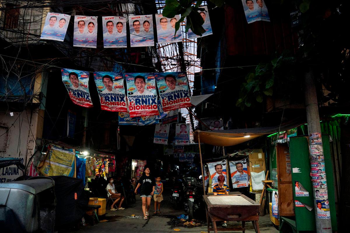 People walk past a street with campaign posters put up, a day before the May 12 midterm elections, in Manila, Philippines, May 11, 2025. REUTERS/Lisa Marie David