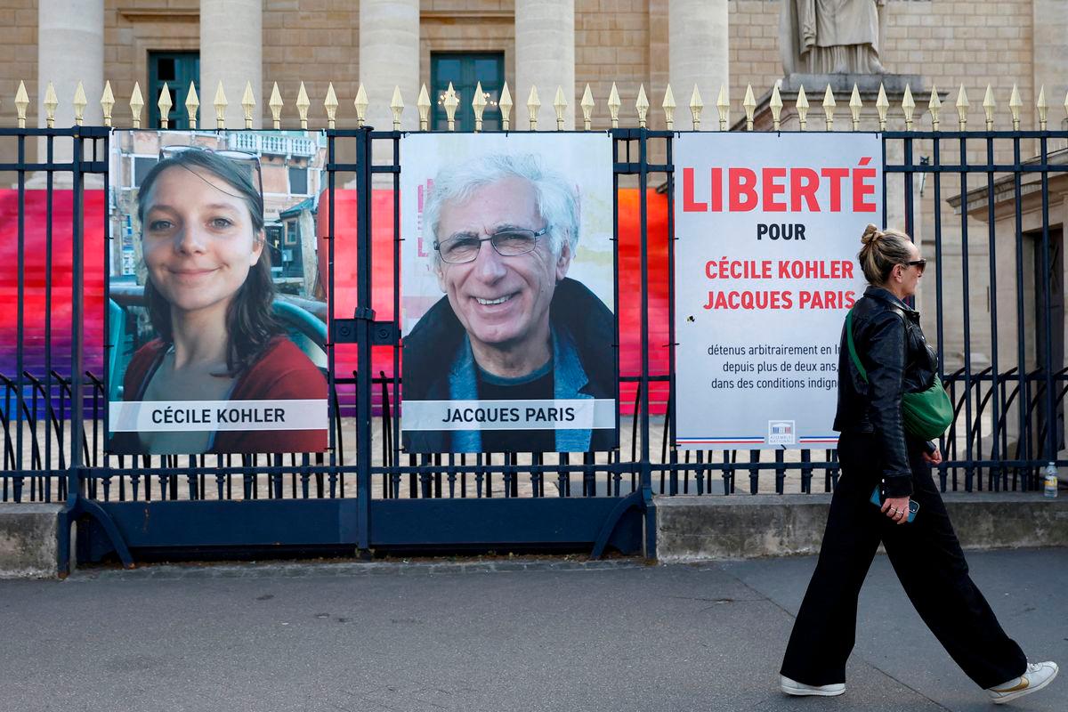 A woman walks past posters with the portraits of Cecile Kohler and Jacques Paris, two French citizens held in Iran, on the day of support rallies to mark their three-year detention and to demand their release, in front of the National Assembly in Paris, France, May 7, 2025. REUTERSpix