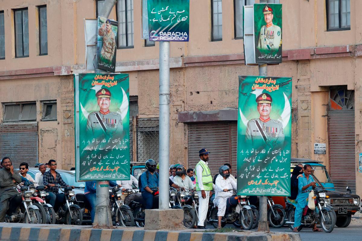 A police officer stands in front of the traffic, next to posters of the Chief of Army Staff of Pakistan Asim Munir, in Karachi, Pakistan May 20, 2025. REUTERSpix