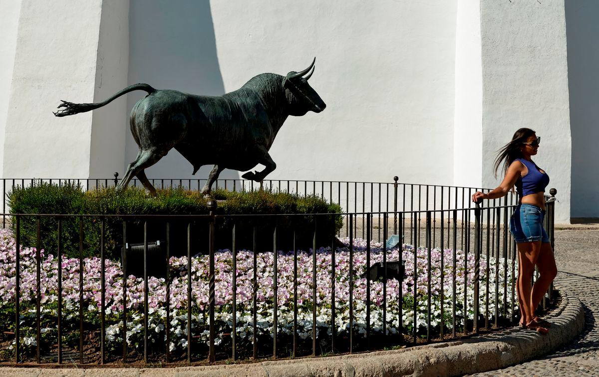 For representational purposes only. A tourist poses for a photo in front of the statue of a bull outside of a bullring. REUTERSpix