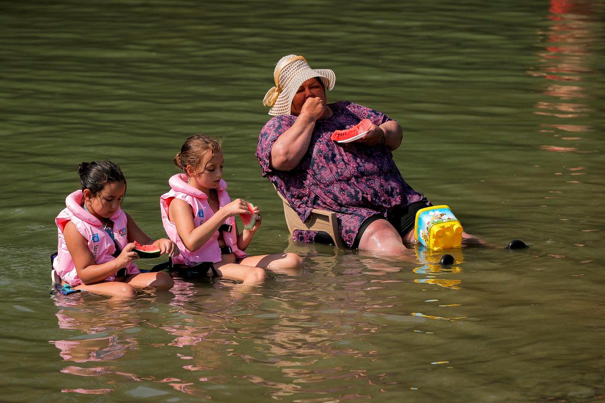 People cool off and eat watermelon in the Erenik River during the heat wave, near Gjakova, Kosovo June 25, 2025. REUTERS/Valdrin Xhemaj
