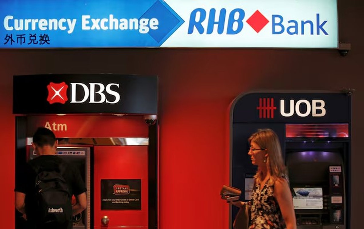 A man uses a DBS automated teller machine next to a United Overseas Banking (UOB) teller, near an RHB Capital Bhd currency exchange booth in Singapore January 5, 2016. - REUTERS
