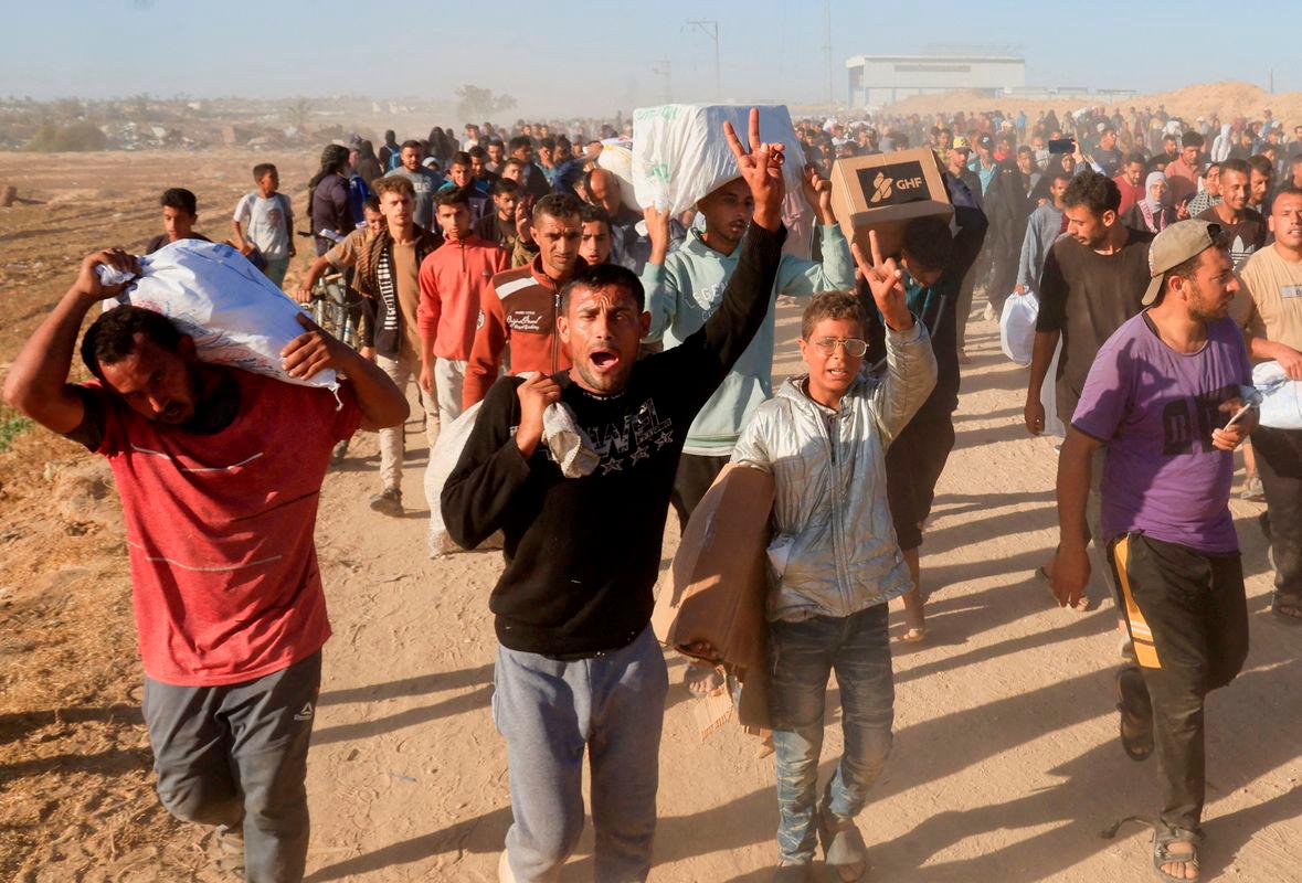 Palestinians carry aid supplies from the U.S.-backed Gaza Humanitarian Foundation, in Khan Younis, in the southern Gaza Strip - Reuterspix