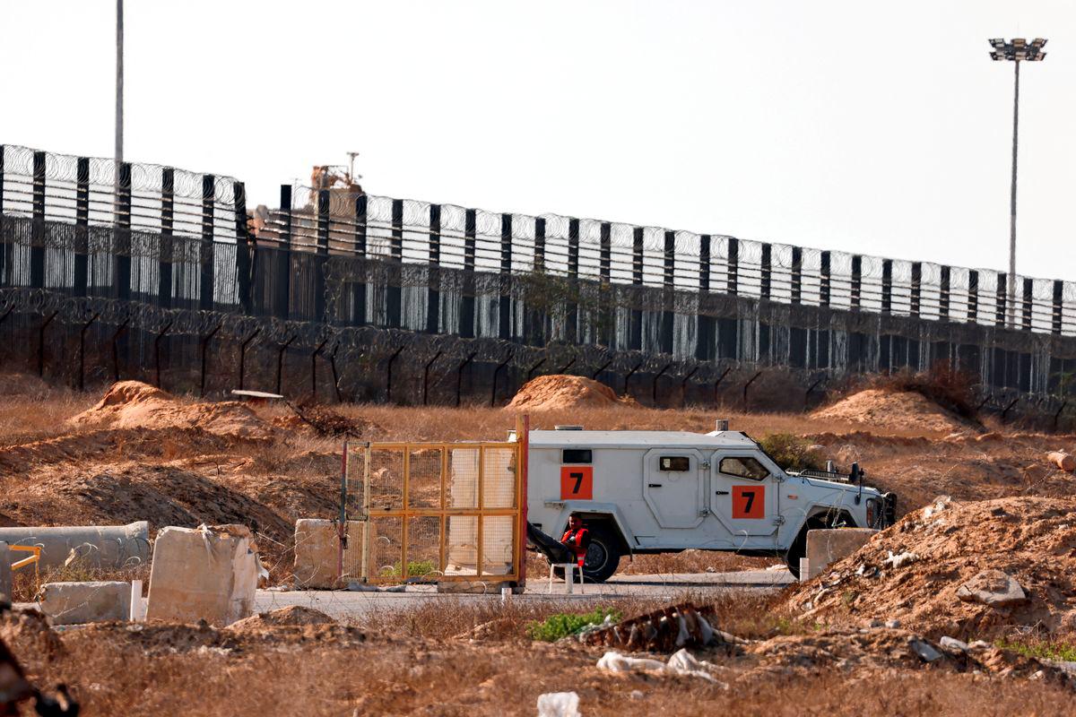 A Gazan man sits next to a gate and an armored vehicle by the Philadelphia road near Kerem Shalom crossing where parcels of humanitarian aid await to be transferred into Gaza from Israel, July 24, 2025. - REUTERSPIX