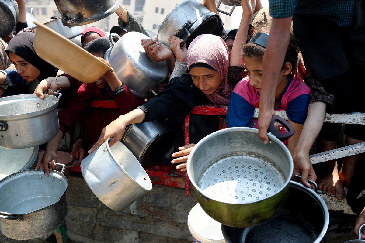 Palestinians wait to receive food from a charity kitchen, amid a hunger crisis, in Gaza City, July 26, 2025. - REUTERS