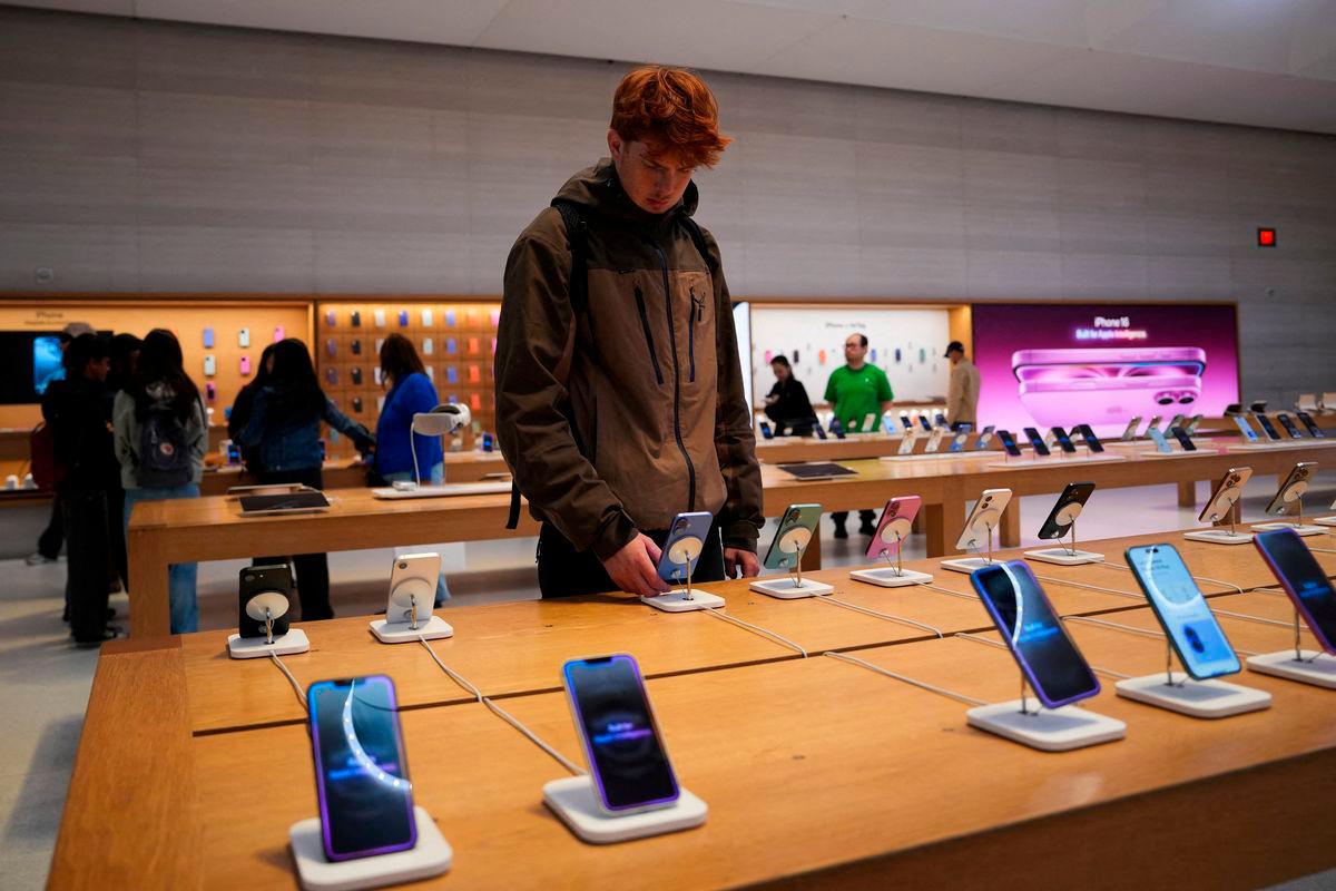 FILE PHOTO: A person looks at iPhones in the Apple Fifth Avenue store in New York City, U.S., May 23, 2025 - REUTERS