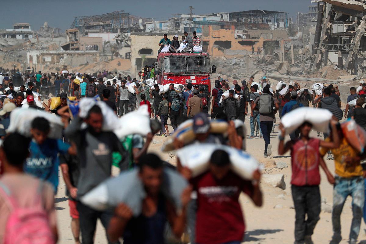 Palestinians carry aid supplies that entered Gaza through Israel, in Beit Lahia, northern Gaza Strip, August 2, 2025. - REUTERS/Mahmoud Issa