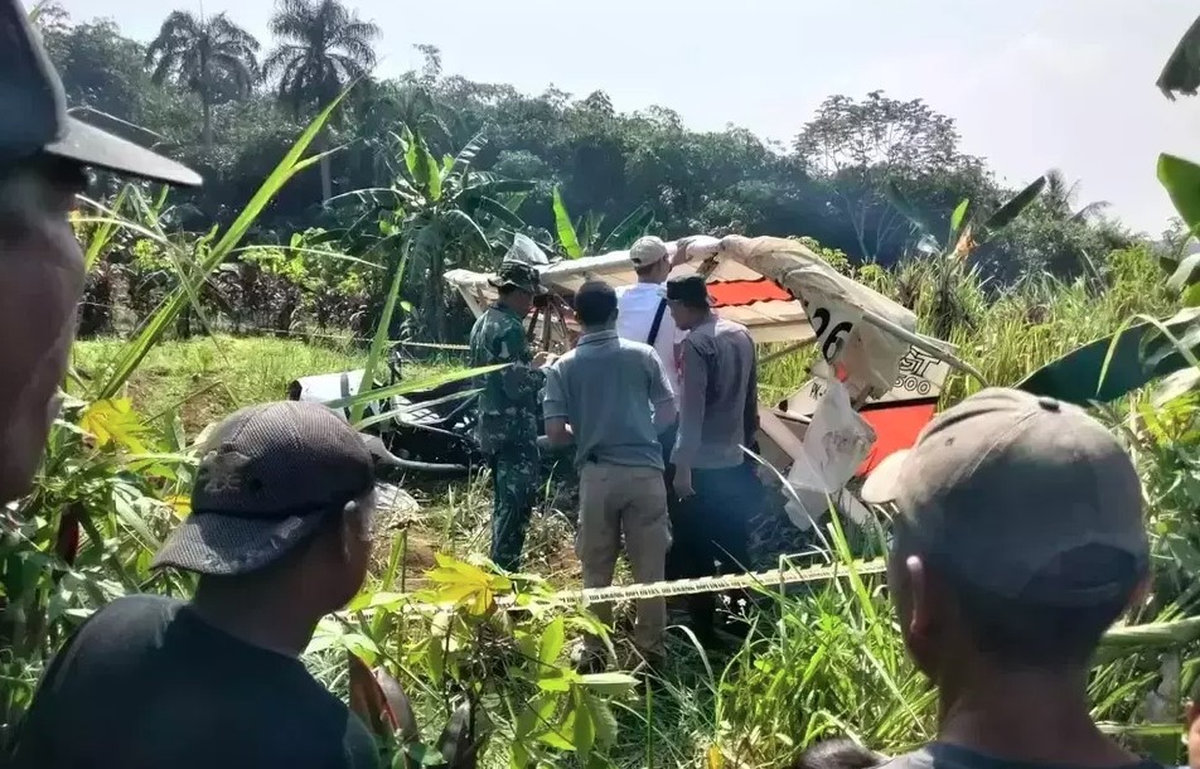 Security personnel inspect the wreckage of a hang glider that crashed into a public cemetery in Ciampea District, Bogor, West Java, on Sunday, Aug. 3, 2025. (Credit: B-Universe piv via Jakarta Globe)