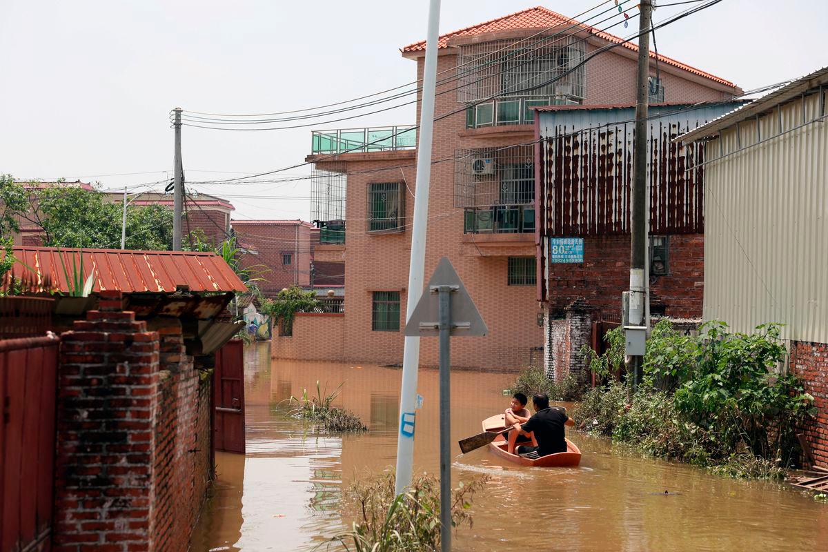 A man paddles in a boat with a boy as they make their way through floodwater after days of heavy rainfall, at a village in Qingyuan, Guangdong province, China August 8, 2025. Florence Lo/ REUTERS