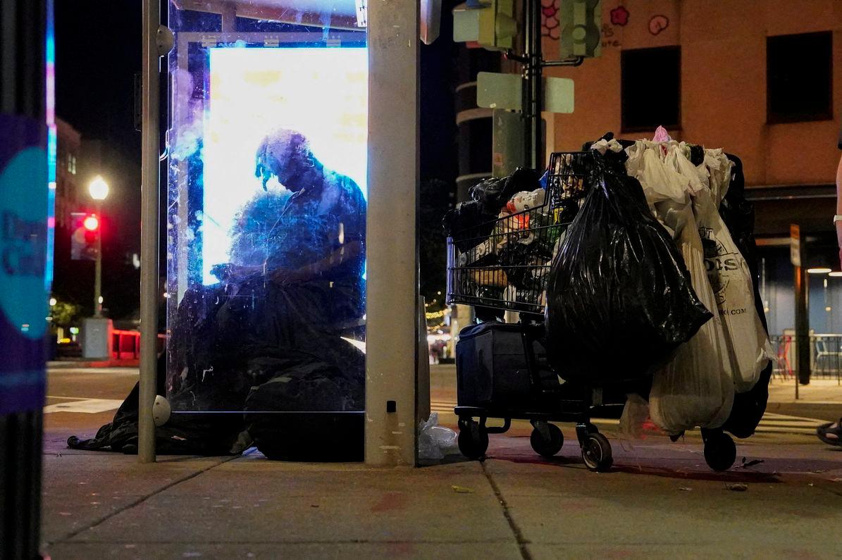 A homeless person sits at a bus stop in Dupont Circle, in Washington, D.C., U.S., August 11, 2025. - REUTERSPIX