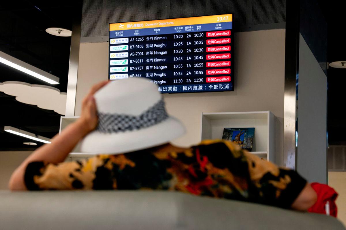 A woman sits in front of a screen displaying information on cancelled domestic flights, as Typhoon Podul approaches the country, in Taipei, Taiwan August 13, 2025. - REUTERSPIX