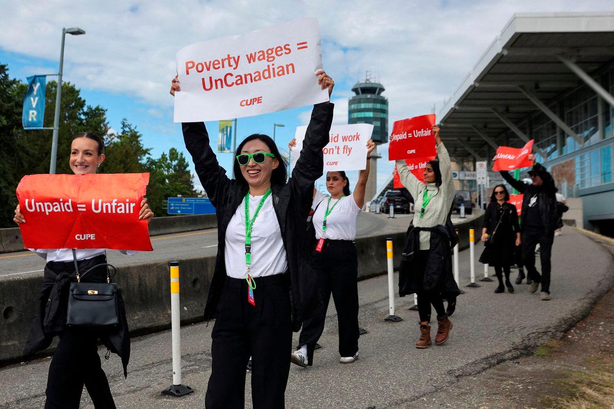 Demonstrators hold placards on the day the strike begins, after the union representing more than 10,000 of Air Canada’s flight attendants failed to reach an agreement with the airline, at Vancouver International Airport in Richmond, British Columbia, Canada, August 16, 2025. REUTERS/Chris Helgren