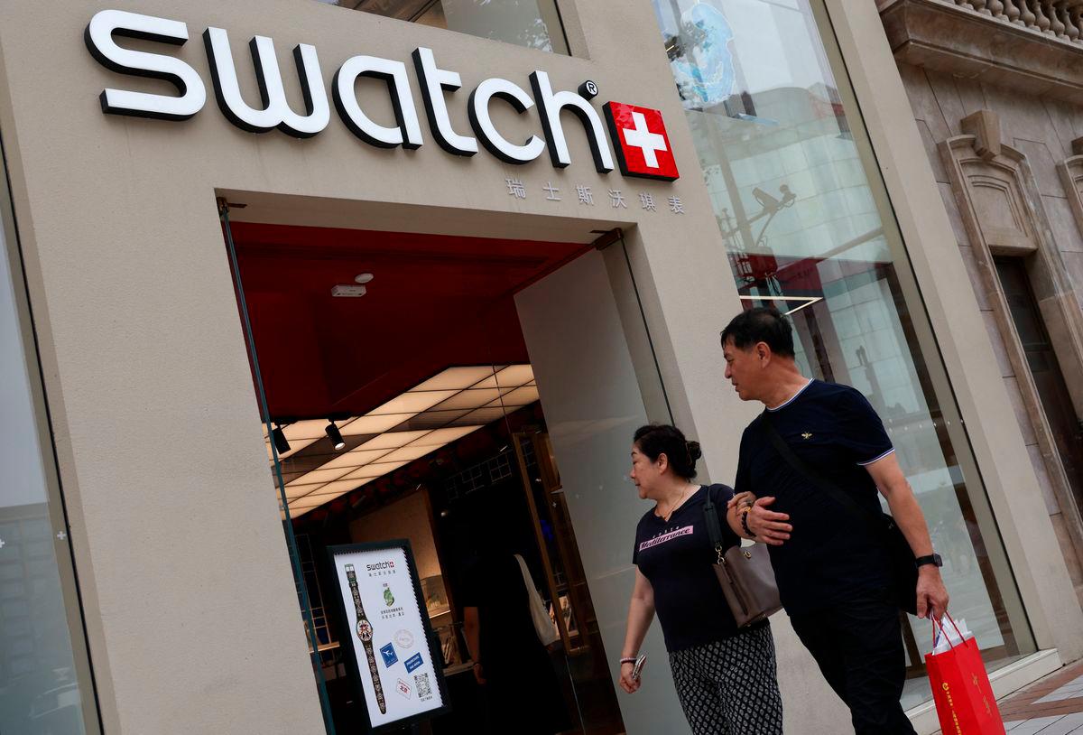People walk past a store of Swiss watchmaker Swatch, in Beijing, China August 18, 2025. REUTERS/Tingshu Wang