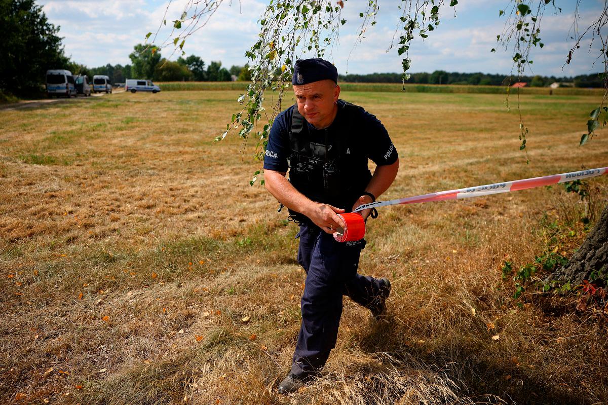 A police officer sets up a police tape, after an unidentified object fell and exploded in a cornfield overnight, according to Polish authorities, in the village of Osiny, eastern Poland, August 20, 2025. - REUTERS/Kacper Pempel