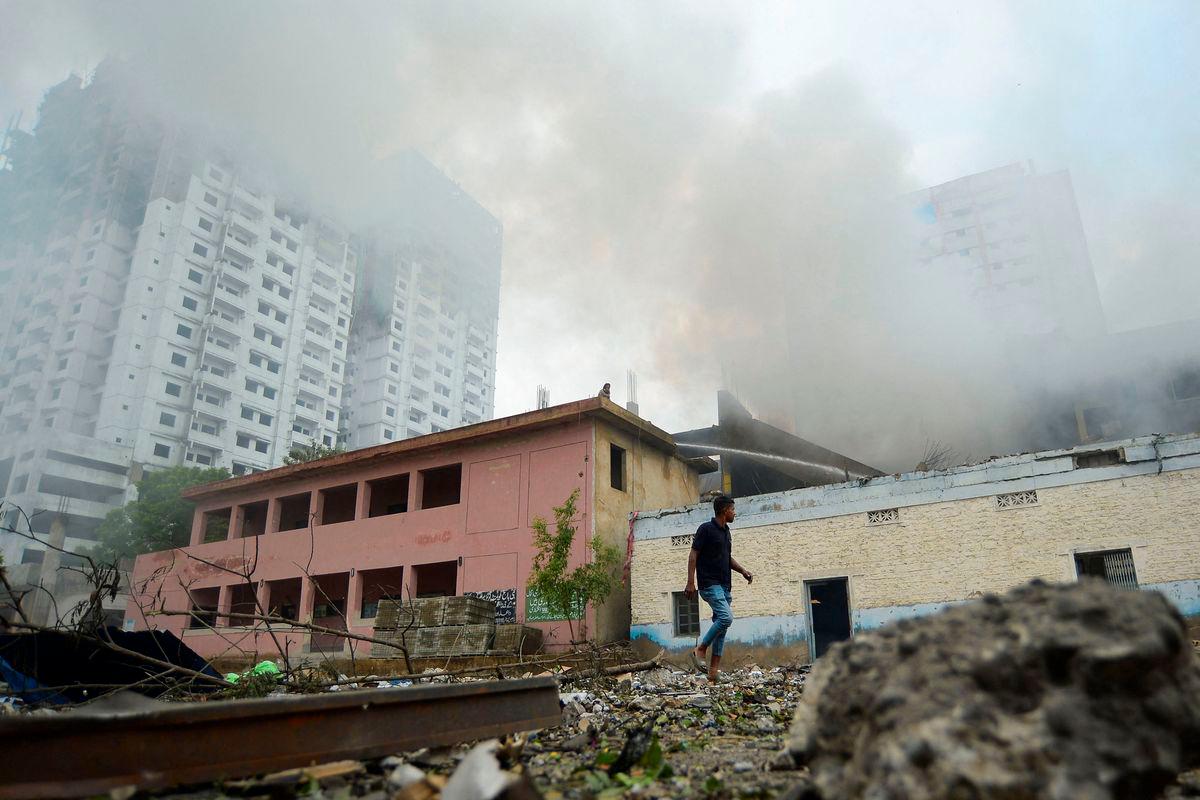 A person walks outside a fireworks warehouse as smoke rises after an explosion, in Karachi, Pakistan August 21, 2025. REUTERS/Imran Ali