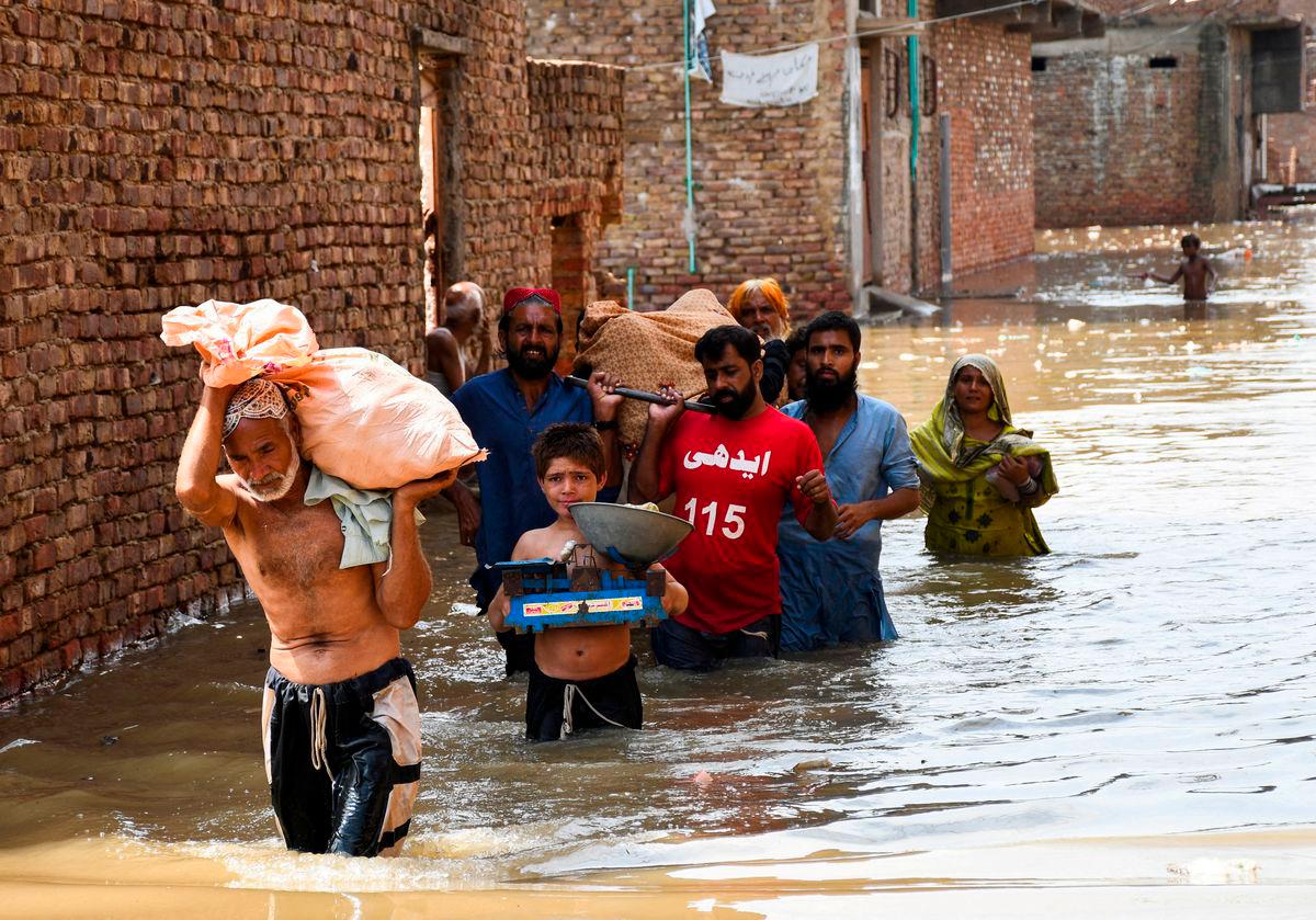 People wade through a flooded street as they carry a woman towards the hospital at Latifabad, Hyderabad, Pakistan, August 22, 2025. REUTERS/Yasir Rajput TPX IMAGES OF THE DAY
