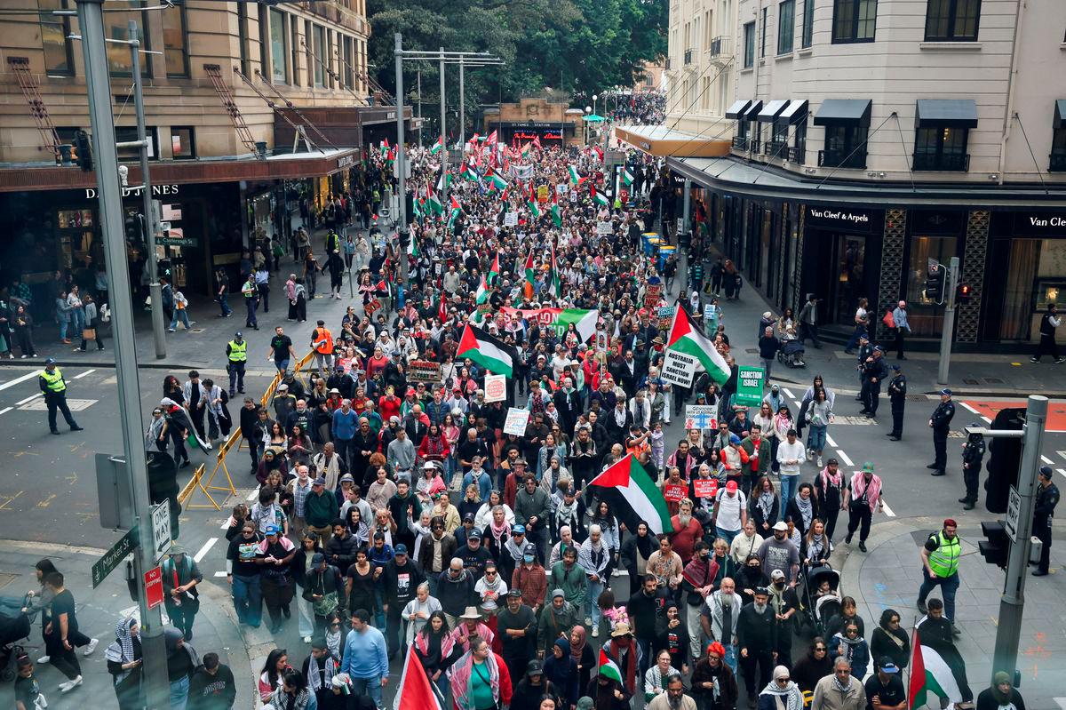 Demonstrators hold placards and flags as they take part in the ‘Nationwide March for Palestine’ protest in Sydney, Australia, August 24, 2025. Picture taken through glass. REUTERS/Hollie Adams