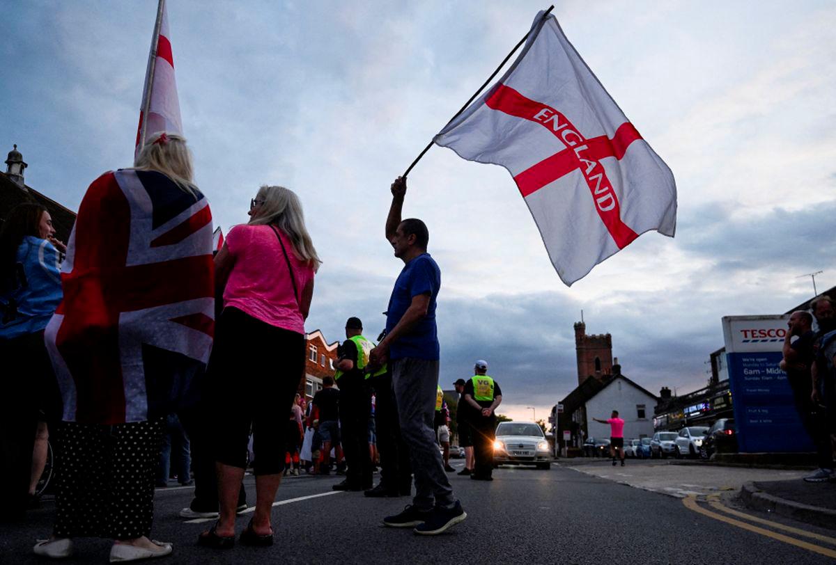 A man waves a flag with 'England' written on it, as protesters gather during an anti-immigration demonstration, following Tuesday's High Court ruling in London that granted a temporary injunction to stop asylum seekers from being housed at the The Bell Hotel, in Epping, Britain, August 24, 2025. - REUTERSPIX