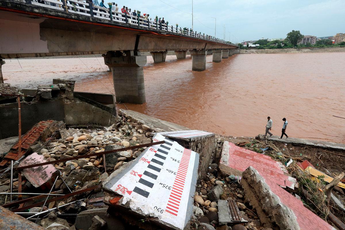 Lelaki berjalan melepasi penanda air yang rosak di sepanjang tebing Sungai Tawi selepas hujan lebat di Jammu, Kashmir India, 27 Ogos 2025. REUTERS/Stringer