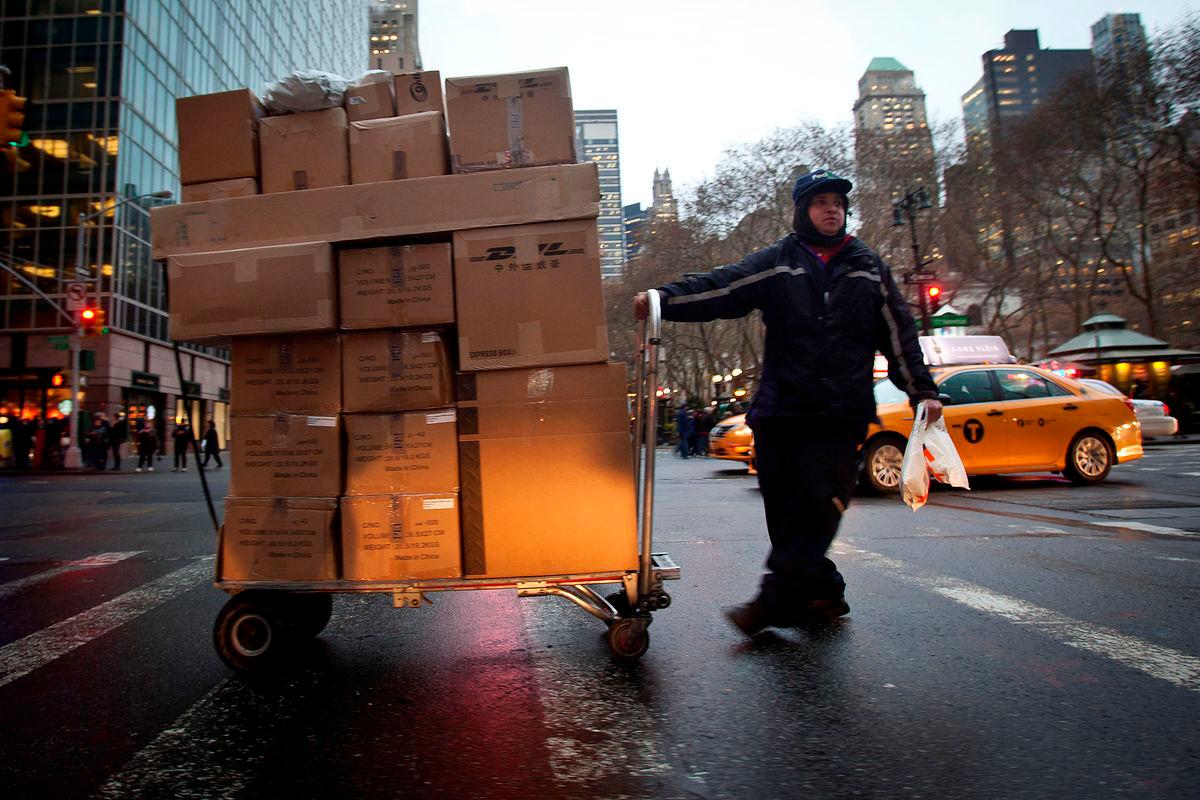 FILE PHOTO: A delivery person wheels a trolley full of packages across 42nd Street in New York December 2, 2014. REUTERS/Carlo Allegri/File Photo/File Photo