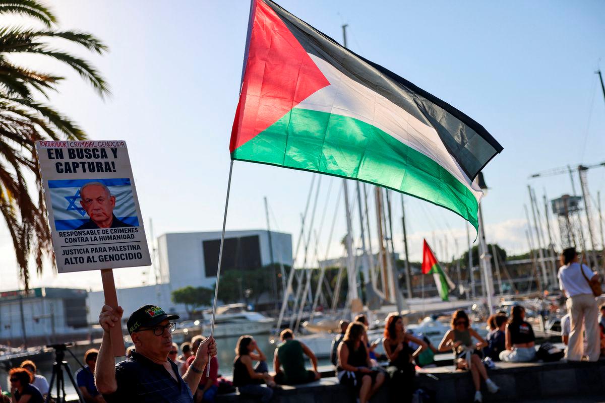 Fernando Barrena, 76, holds a Palestinian flag and a sign with the image of Israeli Prime Minister Benjamin Netanyahu, ahead of the Global Sumud Flotilla, a humanitarian expedition to Gaza, at the port of Barcelona, Spain August 31, 2025. REUTERS/Nacho Doce